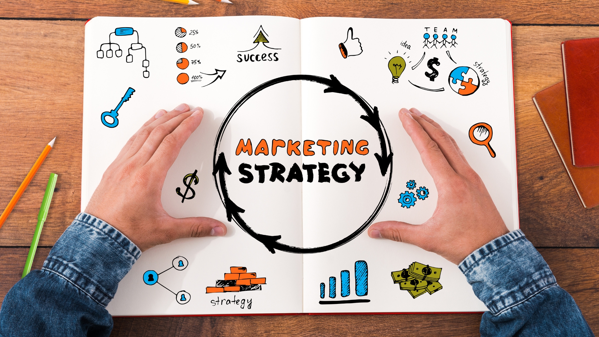 marketing consultant with hands hovering over an open notebook with marketing icons and the words marketing strategy in the center